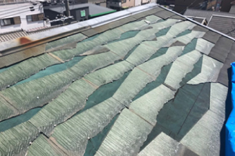 台風によって大部分のスレート屋根が剥がれ、緑色の防水紙が剥き出しに